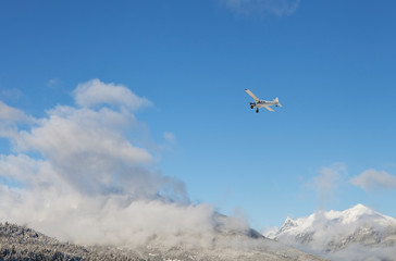 Small airplane flying over Alaskan mountains in winter