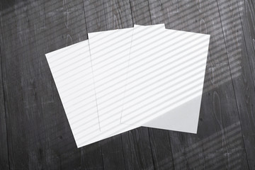 Blank poster flyer letterheads with window overlay shadow on light wooden desk as template for design presentation, event promotion, portfolio etc.