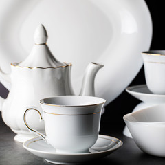 White porcelain tea set-folded cups and saucers and teapot.