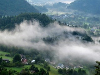 Morning mist walks above the village near Bled lake, Slovenia