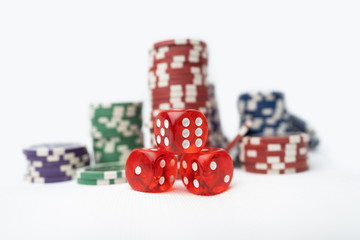Three dice and Poker chips on a white background