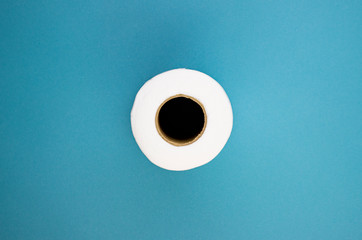 roll of white toilet paper on a blue background, top view. paper for hygiene and cleanliness