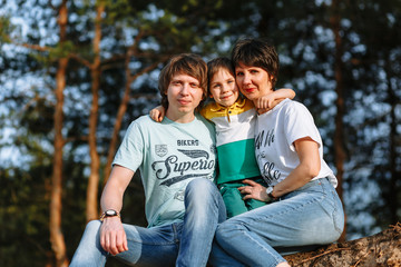 Fototapeta premium Father mother and son sit against the background of the forest