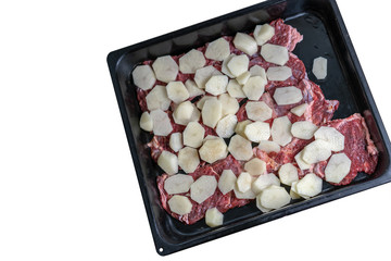 Raw meat with potatoes on a baking sheet on a white background