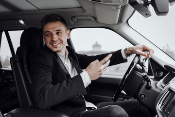 Happy guy holding mobile phone in car
