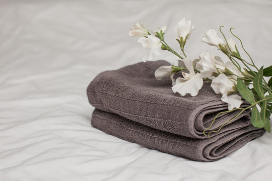  Gray terry towels are stacked on the roof with white pastel linen, a white flower. May 25th day towels. Copy space