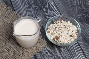 Glass with milk. Nearby in a muesli container. On brushed pine boards.