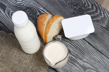 Bottle and glass with milk. Next to slices of ciabatta and cottage cheese. On brushed pine boards.