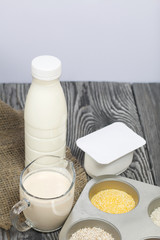 Bottle and glass with milk. Near the cottage cheese and a container with cereals: buckwheat, rice, barley and corn. On brushed pine boards.