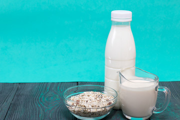 Bottle and glass with milk. Nearby in a muesli container. On brushed pine boards.