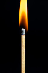 Single matchstick on fire in front of black background.