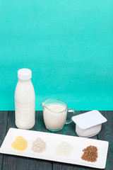 Bottle and glass with milk. Near the cottage cheese and a container with cereals: buckwheat, rice, barley and corn. On brushed pine boards.