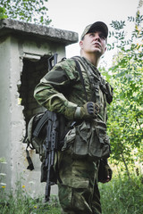 a military man walks through abandoned buildings in the forest
