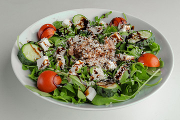 Healthy greens salad on a white plate on a white background