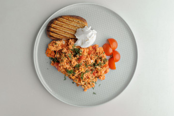 Omelet with tomatoes, cheese and a sandwich on a white plate on a white background