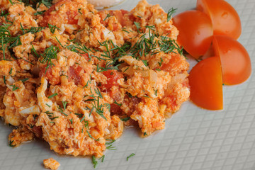 Omelet with tomatoes, cheese and a sandwich on a white plate on a white background