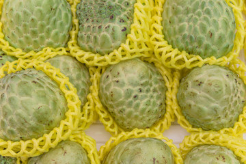 Sugar apple or sweetsop in foam mesh sleeves at fruit stall in Little India, Singapore