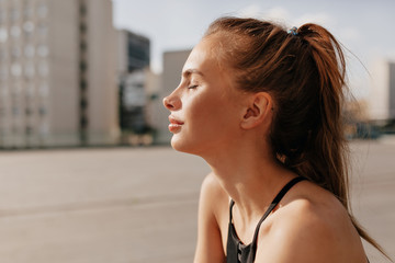 Fototapeta premium Close up portrait of pretty woman relaxing sunshine in the morning before training. Portrait motivated excited young woman in sportswear smiling, in sunny morning outside