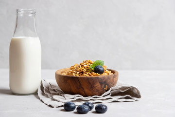Homemade cooked healthy granola for breakfast in a wooden bowl on the table and near a bottle of milk. Place for text. Fitness food, snack