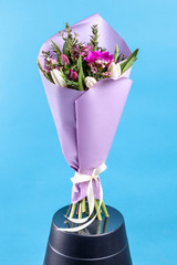 bouquet of flowers with tulips and anemones in a lilac package on a blue background. high quality.