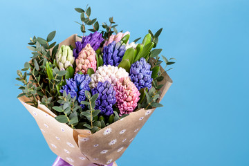 bouquet of flowers with multi-colored hyacinths in a craft paper package on a blue background. close-up, high quality.