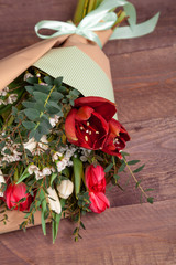 a bouquet of flowers with tulips, chamelaucium, Amaryllis and eucalyptus on a wooden table. high quality