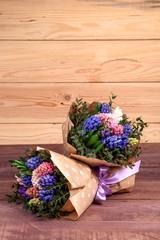 bouquet of flowers with multi-colored hyacinths in a craft paper package on a wooden background. high quality.