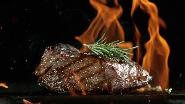 Close-up of falling tasty beef steak on iron cast grate, super slow motion, filmed on high speed cinematic camera at 1000 fps.