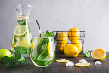 Detox water or lemonade with lemon mint, citrics in glass on grey background.