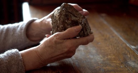 close-up of old hands of an elderly man twisting a stone. An old stone Hammer an elder man holds in his hands. Archaeology. Study of ancient objects