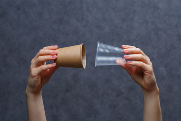 Zero waste concept. Wooden cutlery versus plastic cutlery. Eco-friendly disposable tableware made of bamboo wood and paper on a gray background. Caring for the environment. Recycling problem.