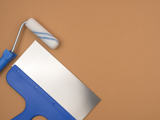 Spatula and roller for painting. Beige background.