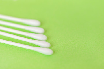 White cotton earbuds on pastel lime background, closeup