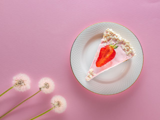 flat lay of strawberry pie on the white plate and three dandelions on the pink background with copy space