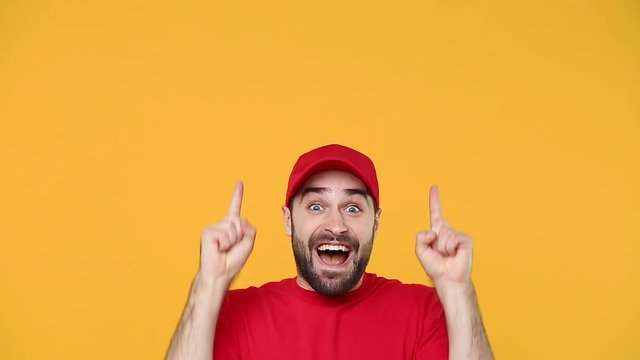 Delivery young guy man in red cap blank t-shirt uniform workwear pointing hands on workspace isolated on yellow background studio Professional male deliveryman employee working courier Service concept