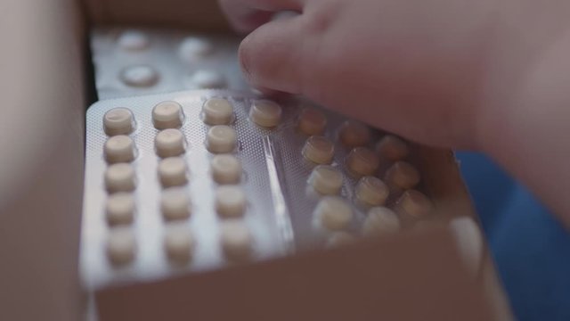 Kid plays with scattering medicine drugs. Toddler touches pills without parent control. Dangerous situation.