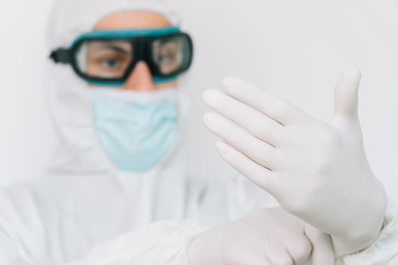 Virologist is weaing in protective clothe during virus pandemic, portrait. Suit, mask, gloves and glasses on white background in clinic or hospital