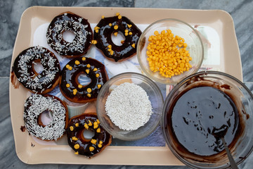 Chocolate donuts with white Sprinkles and liquid chocolate.