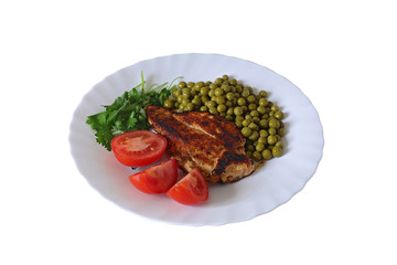 Fried delicious chicken with a side dish of canned green peas with red ripe tomatoes and sprigs of green parsley on a white plate on the table in the room Selective focus isolated