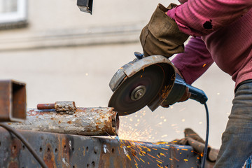 Industrial worker cutting and welding metal with many sharp sparks. Worker cutting metal with grinder.