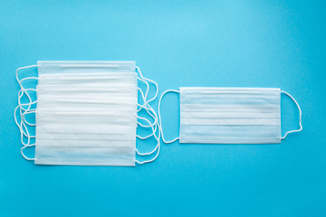 White protective medical masks on a blue background, several in a row on the left,one on the right