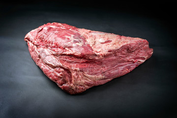 Raw dry aged wagyu beef shoulder clod roast as closeup on black background with copy space