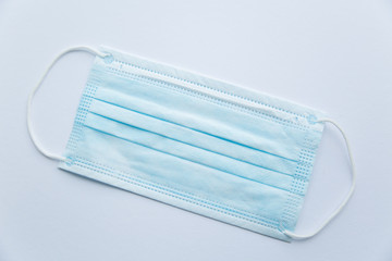 Blue protective medical mask on a white background in the center of a close-up. Personal protective equipment