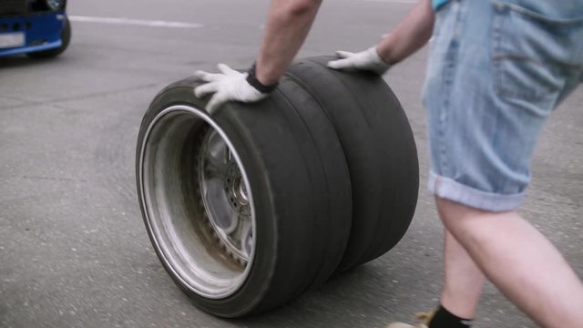 Mechanic rolls two new, freshly assembled wheels along the road close-up shot