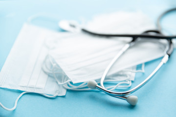 Stethoscope and protective facial surgical masks on a blue background