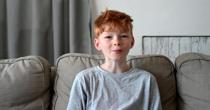 Little boy with red hair sitting in living room having breakfast cereal morning