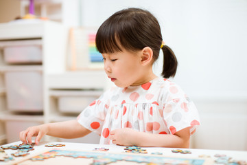 toddler girl playing wooden puzzle at home