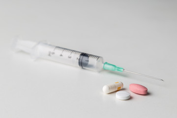 pills together with a medical syringe on a white background