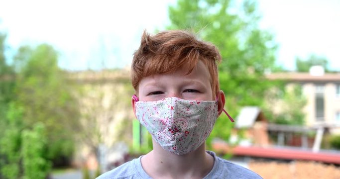 Red hair european boy teenager wearing face mask hand made standing close up. 
