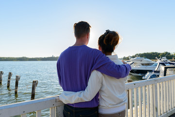Rear view of young multi ethnic couple hugging together at the pier outdoors